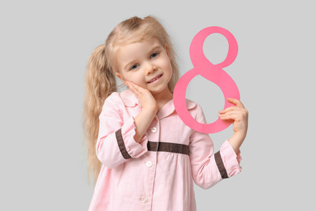 Cute little girl with figure 8 made of paper on gray background. International Women's Day