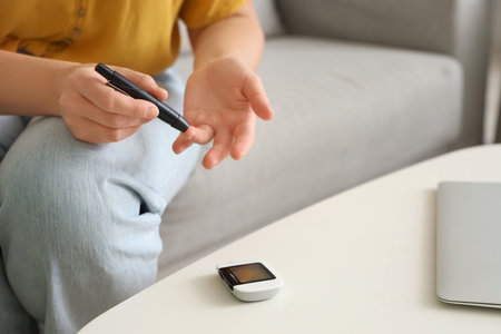 Diabetic woman using lancet pen at home, closeupの写真素材