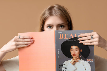Beautiful young woman with stylish jewelry and magazine on brown backgroundの写真素材
