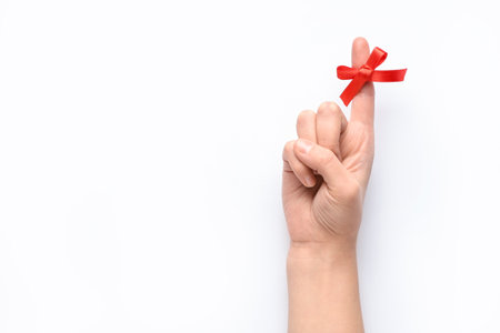 Female hand with red bow on index finger against white background. Reminder conceptの写真素材