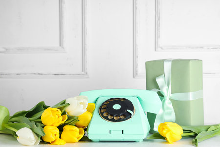 Retro telephone with beautiful tulips and gift box on white table. International Women's Dayの写真素材