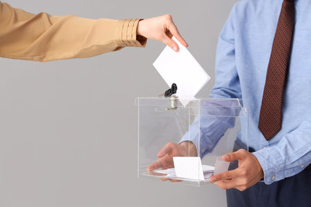 Hand putting voting paper into ballot box on white background. Election conceptの写真素材
