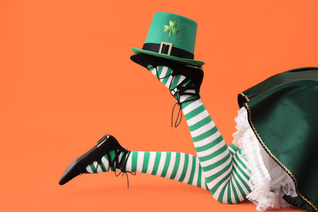Woman in waitress costume with leprechaun's hat on orange background. St. Patrick's Day celebrationの写真素材