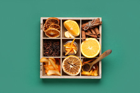 Wooden box with aromatic spices and orange on green backgroundの写真素材