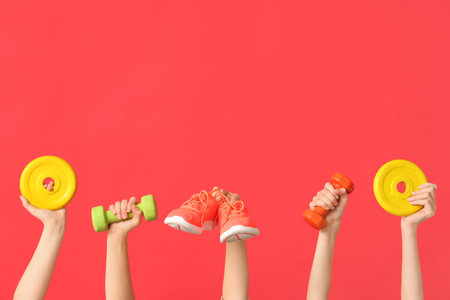 Female hands with sports equipment and shoes on red backgroundの写真素材
