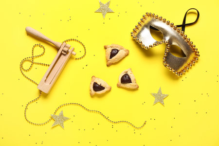 Composition with carnival mask, rattle and Hamantaschen cookies for Purim holiday on yellow backgroundの写真素材