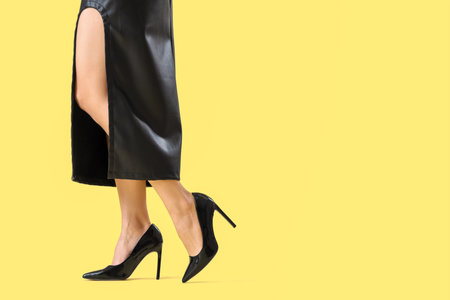 Businesswoman in high heels on yellow backgroundの写真素材