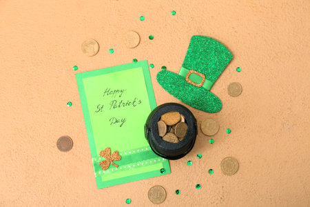 Leprechaun pot with golden coins, paper hat and card on beige background. St. Patrick's Day celebrationの写真素材