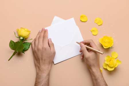 Male hands with envelope, blank card and rose flowers on beige background. International Women's Day celebrationの写真素材