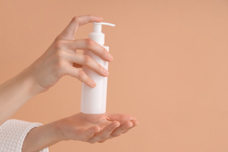 Female hands with bottle of cream on color background, closeupの写真素材
