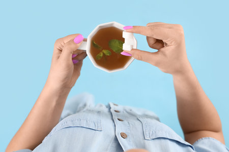 Young woman with sugar and cup of mint tea on blue background, top viewの写真素材
