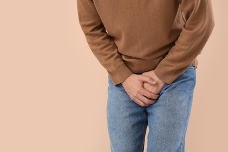 Young man with prostate problem on beige background, closeup. Cancer awareness conceptの写真素材