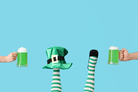 Female legs in green stockings with leprechaun's hat and glasses of beer on blue background. St. Patrick's Day celebrationの写真素材