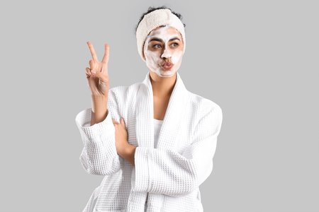 Young African-American woman with cleansing foam showing victory gesture on light backgroundの写真素材