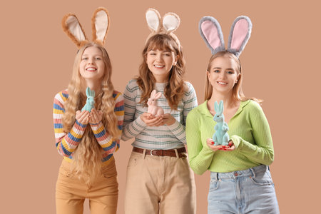 Young girls with Easter bunny ears and toy rabbits on beige backgroundの写真素材