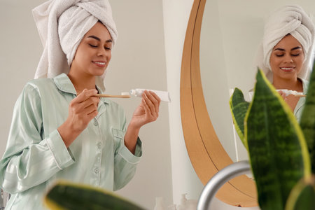 Young African-American woman squeezing tooth paste onto brush after shower in bathroomの写真素材