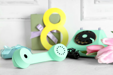 Retro telephone with tulips, gift boxes and figure 8 on white table. International Women's Day