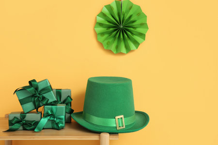 Leprechaun's hat and gift boxes on wooden shelf near orange wall. St. Patrick's Day celebrationの写真素材