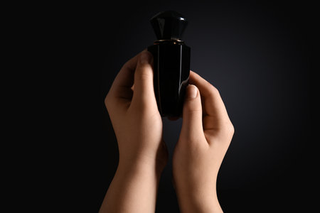 Woman with bottle of perfume on dark backgroundの写真素材