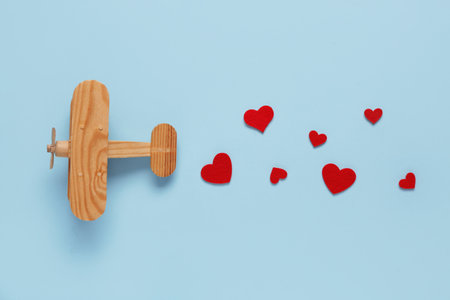 Wooden airplane with paper hearts on blue background. Valentine's Day celebrationの写真素材
