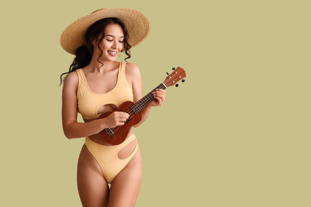 Sexy young woman in swimsuit playing ukulele on green backgroundの写真素材