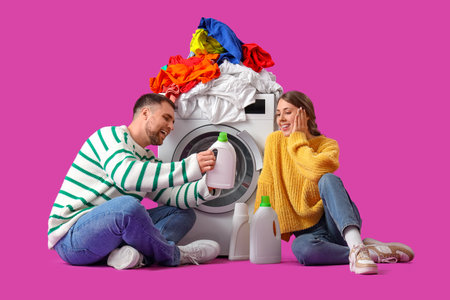 Young couple doing laundry on magenta backgroundの写真素材
