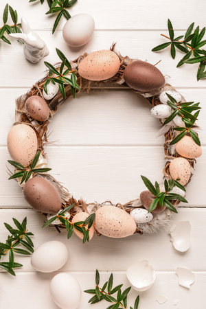 Stylish Easter wreath decorated with eggs and flowers on white wooden table. Top viewの写真素材