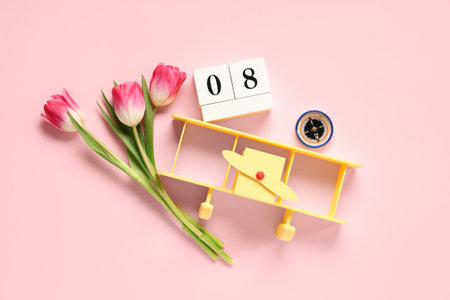 Composition with toy plane, tulip flowers and calendar with date of International Women's Day on pink backgroundの写真素材