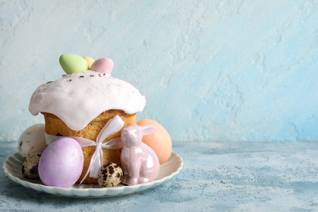 Composition with delicious decorated Easter cake, porcelain bunny and painted eggs in plate on color...