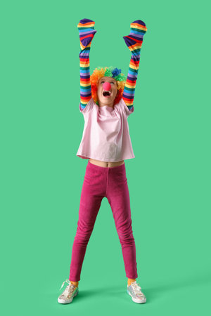 Funny girl in clown costume on green background. April Fool's Day celebrationの写真素材