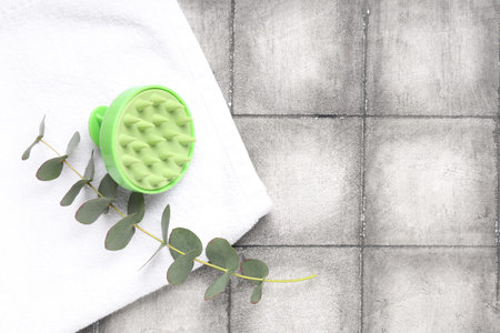 Hair scalp massager with towel and eucalyptus on gray tile backgroundの写真素材