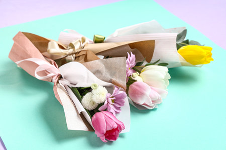 Mini bouquets of beautiful spring flowers in wrapping paper on turquoise background. International Women's Dayの写真素材