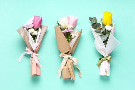 Mini bouquets of beautiful spring flowers in wrapping paper on turquoise background. International Women's Dayの写真素材