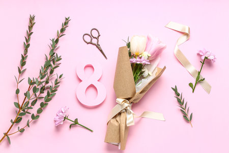 Mini bouquet of beautiful spring flowers in wrapping paper with eucalyptus, scissors and figure 8 on...