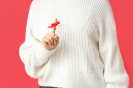 Woman with red bow on index finger against red background. Reminder conceptの写真素材