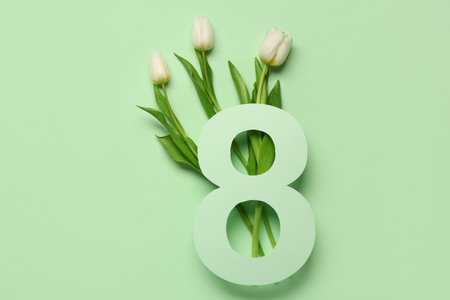 Figure 8 made of paper and beautiful white tulips on green background. International Women's Day