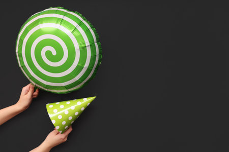 Female hands with balloon and party hat on black backgroundの写真素材