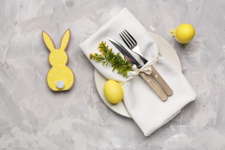 Stylish table setting with Easter eggs, napkin and cutlery on grunge gray background