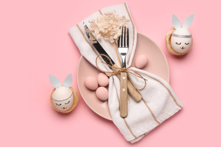 Beautiful table setting with Easter eggs, napkin and cutlery on pink background