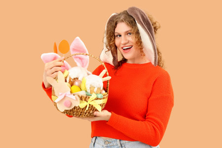 Beautiful young happy woman in bunny ears with Easter basket on beige background