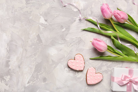 Tulip flowers with gift box and cookies in shape of hearts on gray grunge background. International Women's Day celebrationの写真素材