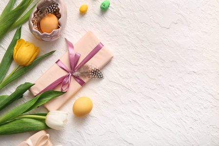 Easter eggs with gift box and tulip flowers on white background