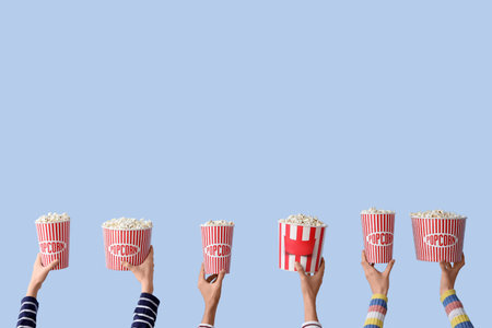 Many hands with buckets of popcorn on blue backgroundの写真素材