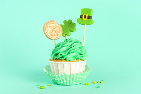 Tasty green cupcake with decor for St. Patrick's Day on turquoise backgroundの写真素材