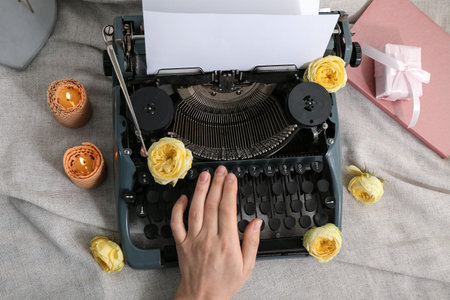 Female hand with vintage typewriter, roses and candles on clothの写真素材