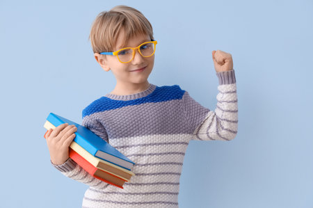 Cute little boy in eyeglasses with stack of books on color background