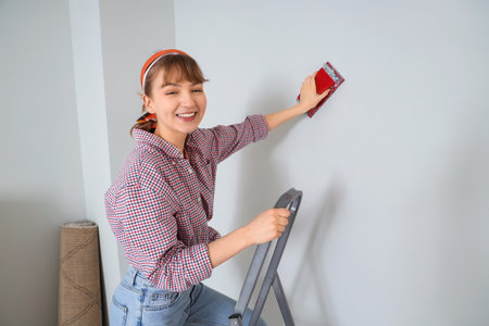 Young woman using jigsaw during repair in roomの写真素材