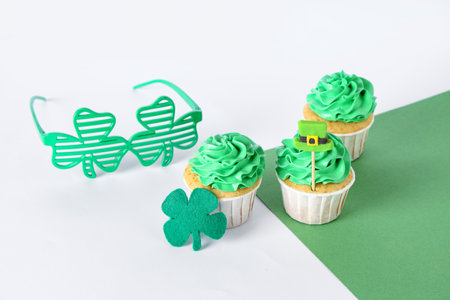 Tasty cupcakes with clover and eyeglasses for St. Patrick's Day on color backgroundの写真素材