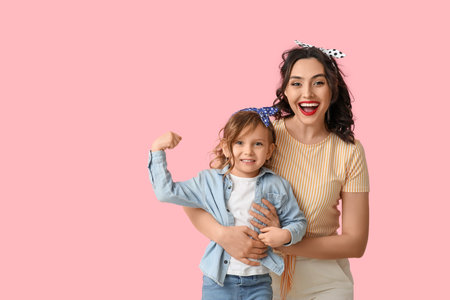Beautiful pin-up woman and her daughter showing muscles on pink background
