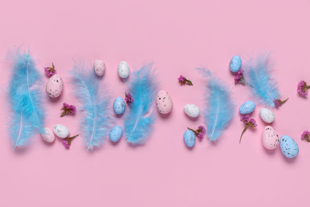 Easter eggs with flowers and feathers on pink background